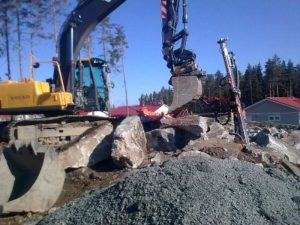 Toinen kuva pihan louhintatöitä, joita tehdään poravaunun ja kaivinkoneen avulla.